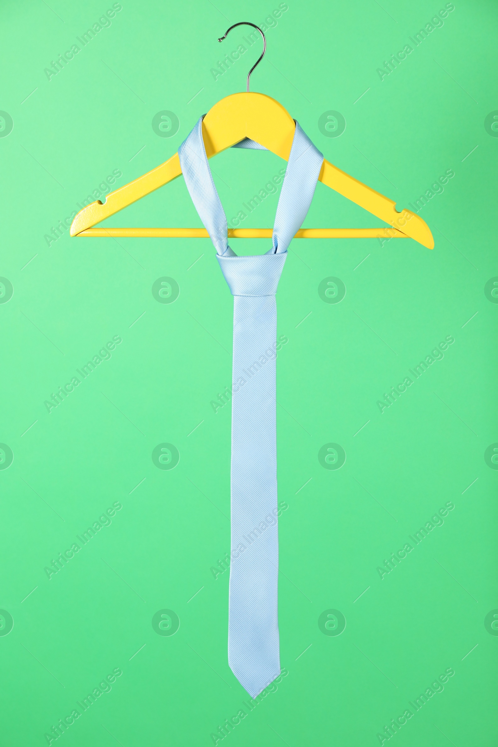 Photo of Hanger with light blue tie on green background