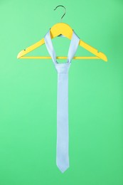 Hanger with light blue tie on green background