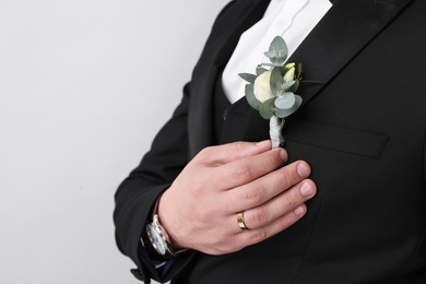 Groom with boutonniere on light grey background, closeup and space for text. Wedding accessory