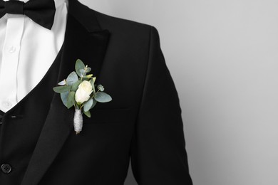 Groom with boutonniere on light grey background, closeup and space for text. Wedding accessory