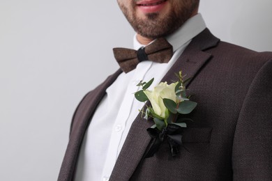 Photo of Groom with boutonniere on light grey background, closeup and space for text. Wedding accessory