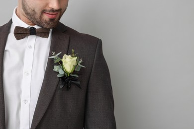 Photo of Groom with boutonniere on light grey background, closeup and space for text. Wedding accessory