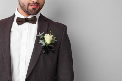 Groom with boutonniere on light grey background, closeup and space for text. Wedding accessory
