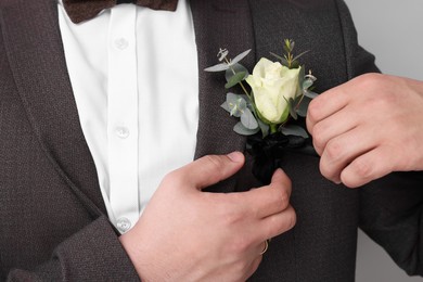 Photo of Groom with boutonniere on light grey background, closeup. Wedding accessory