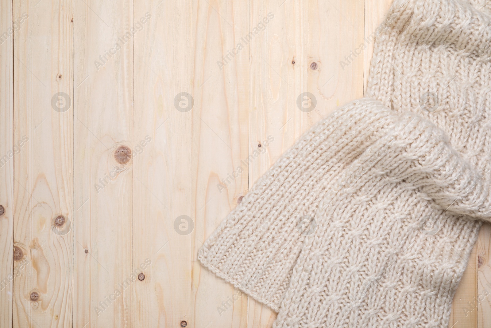 Photo of Beige knitted scarf on wooden table, top view. Space for text