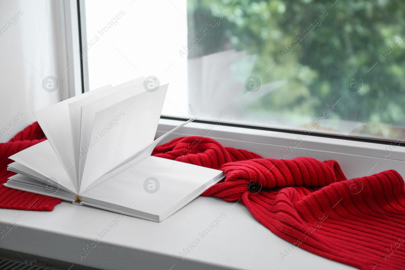 Photo of Red knitted scarf and notebook on windowsill