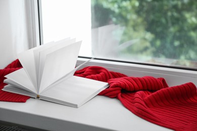 Red knitted scarf and notebook on windowsill