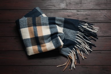 Soft checkered scarf on wooden table, top view