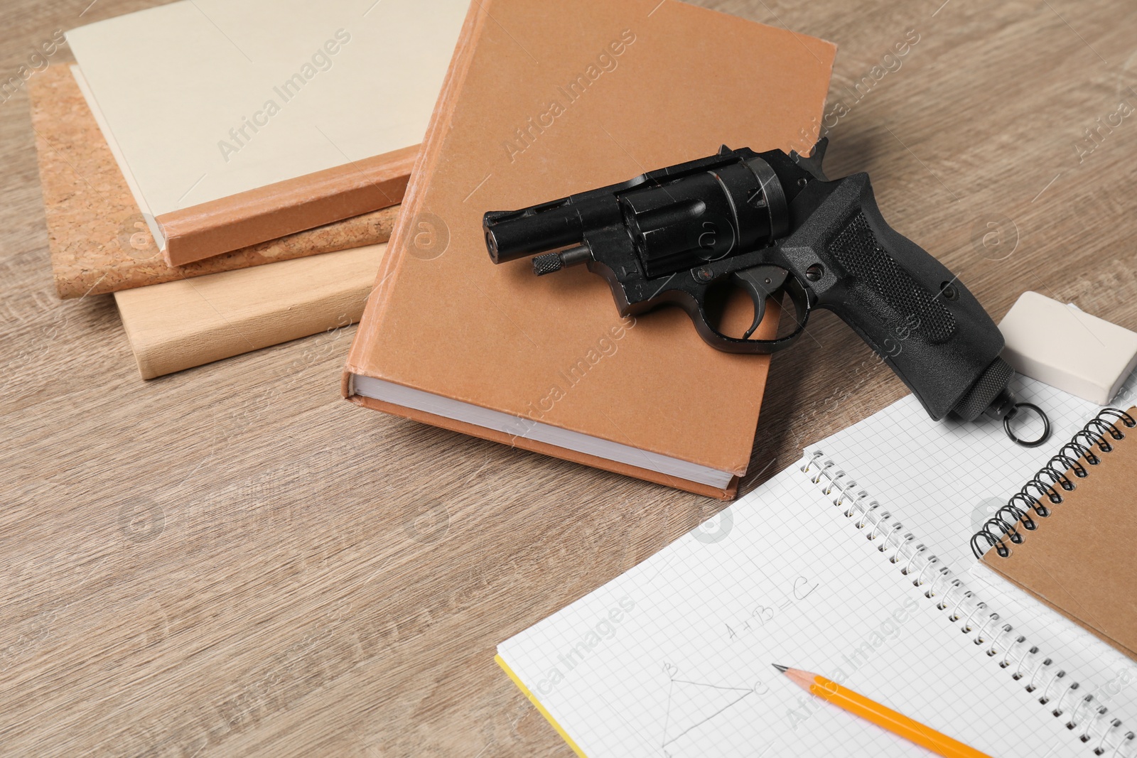 Photo of Gun and school stationery on wooden table