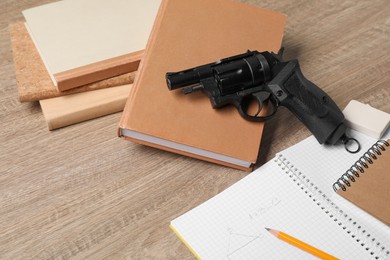 Gun and school stationery on wooden table