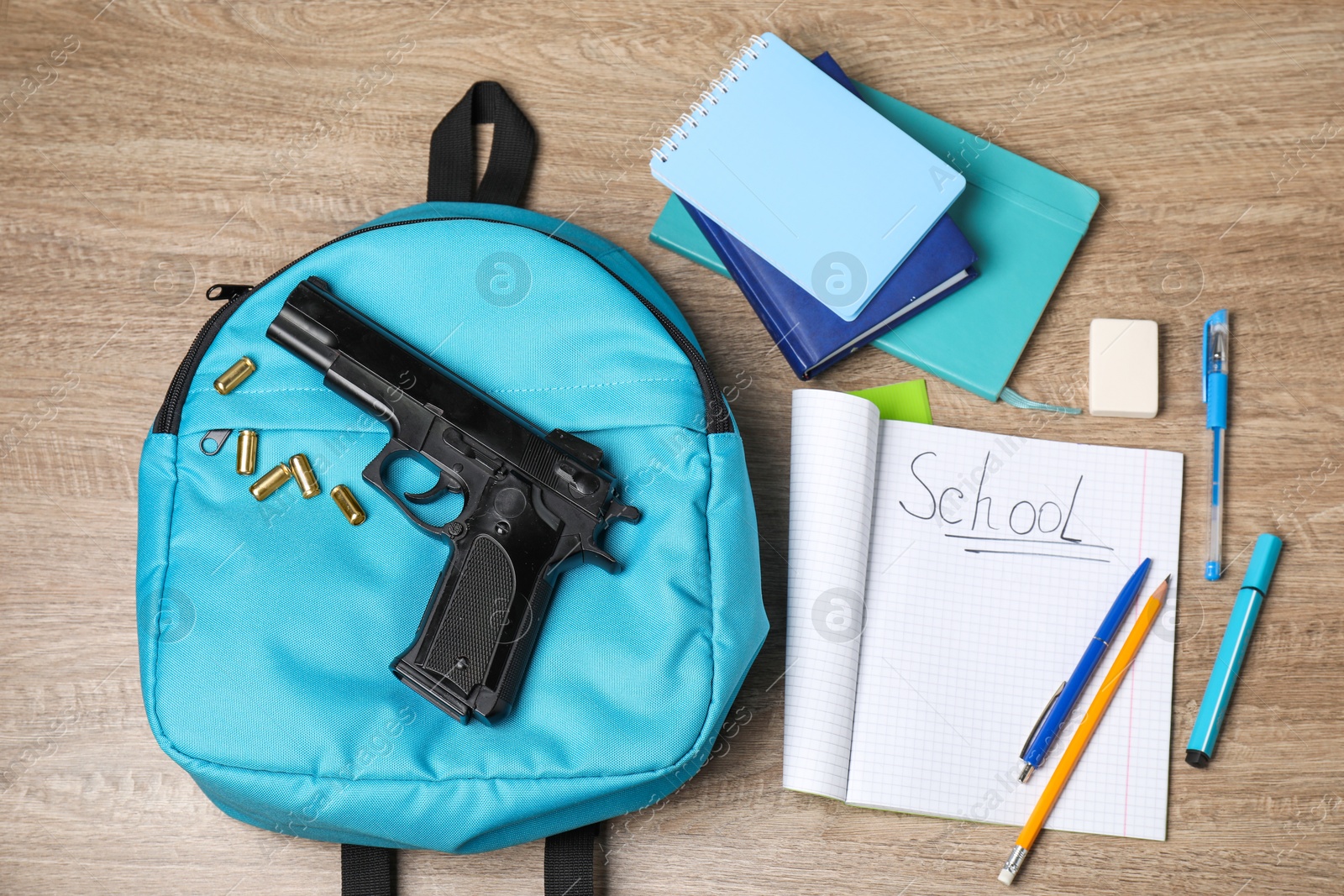 Photo of Gun, bullets and school stationery on wooden table, flat lay