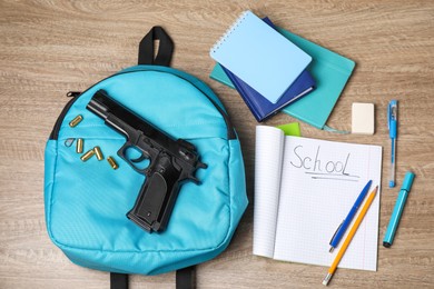 Gun, bullets and school stationery on wooden table, flat lay