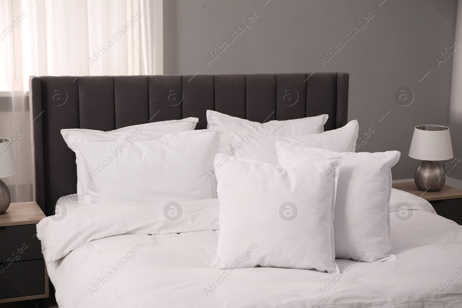 Photo of Many soft white pillows and duvet on bed indoors