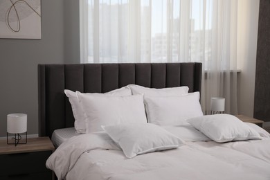 Photo of Many soft white pillows and duvet on bed indoors