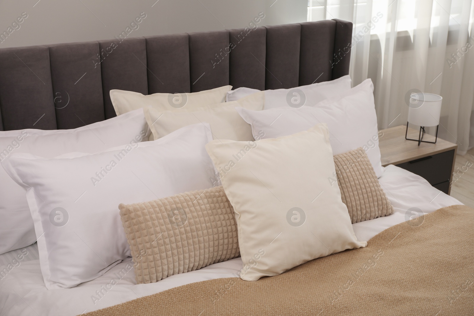 Photo of Many soft white pillows and blanket on bed indoors