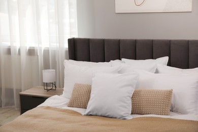 Photo of Many soft white pillows and blanket on bed indoors