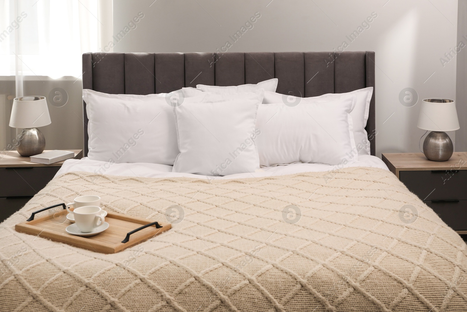 Photo of Many soft white pillows and knitted blanket on bed indoors