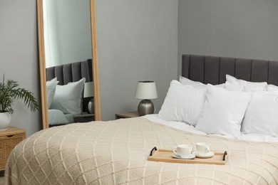 Photo of Many soft white pillows and knitted blanket on bed indoors