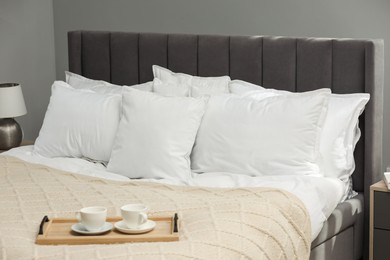 Photo of Many soft white pillows and knitted blanket on bed indoors