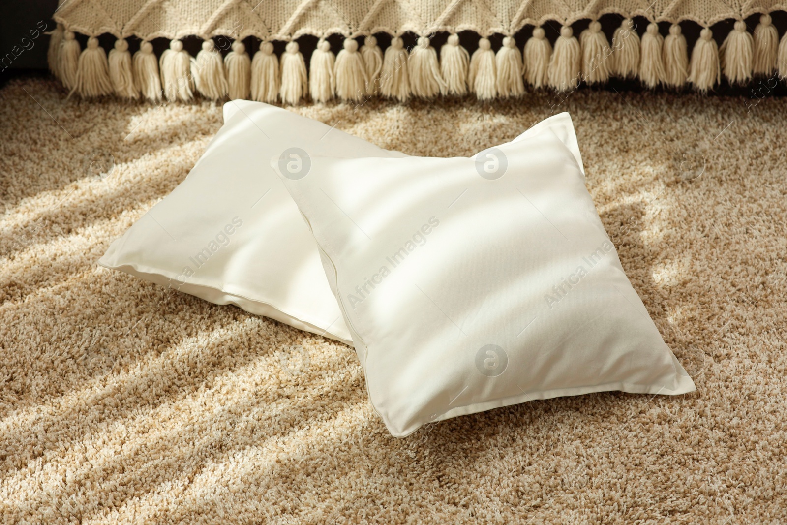 Photo of Soft white pillows on floor in room