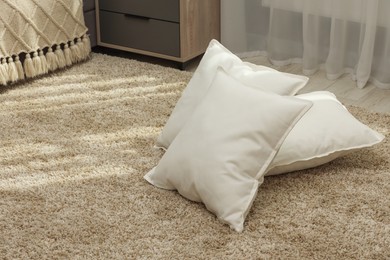 Photo of Soft white pillows on floor in room