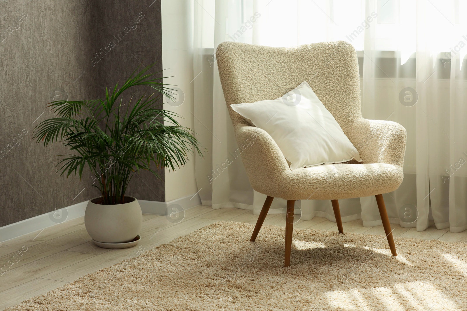 Photo of Soft white pillow on armchair and houseplant near window indoors