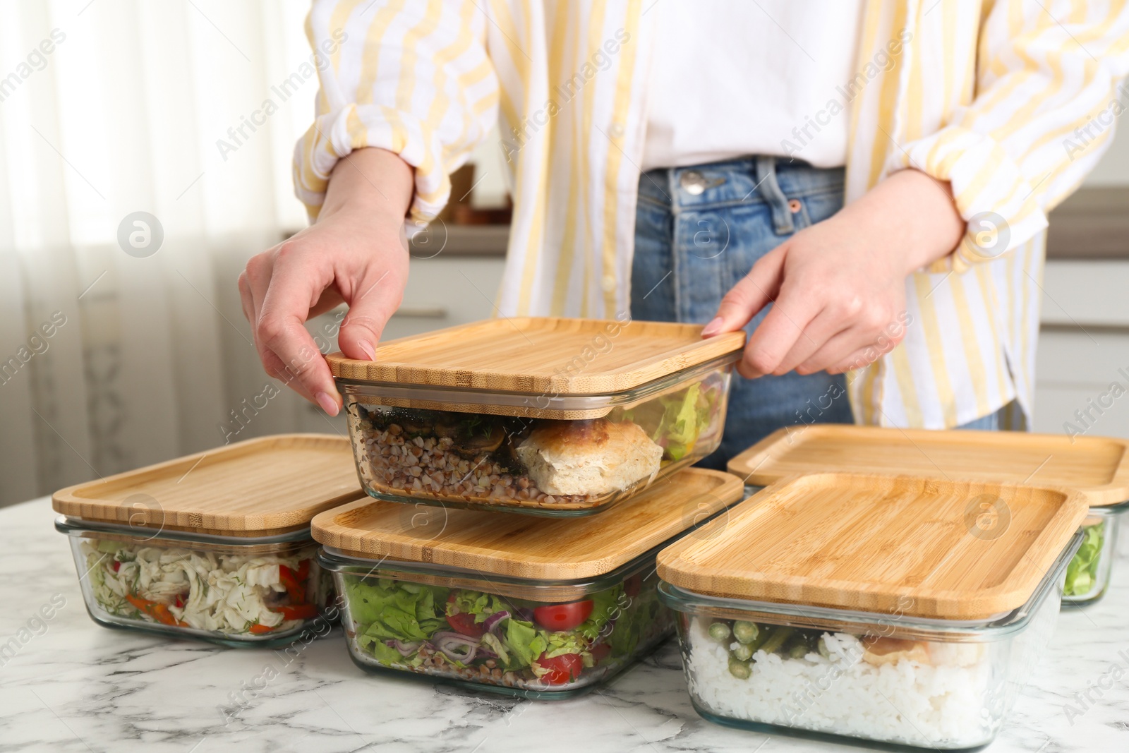 Photo of Healthy food. Woman closing glass container with meal at white marble table, closeup