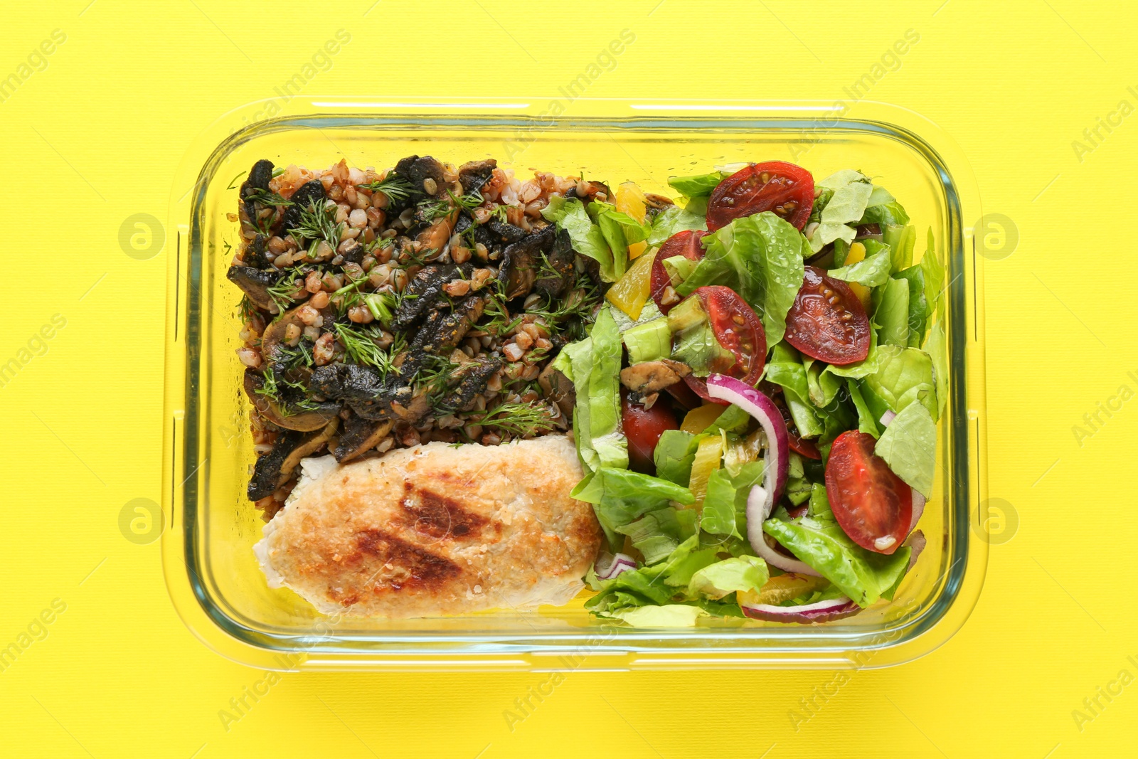 Photo of Healthy meal. Fresh salad, cutlet and buckwheat in glass container on yellow background, top view
