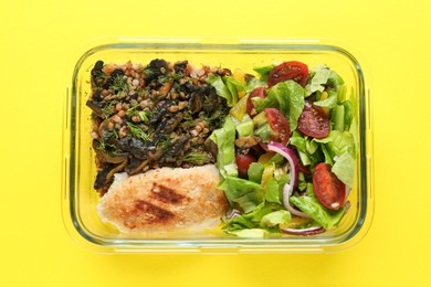 Healthy meal. Fresh salad, cutlet and buckwheat in glass container on yellow background, top view