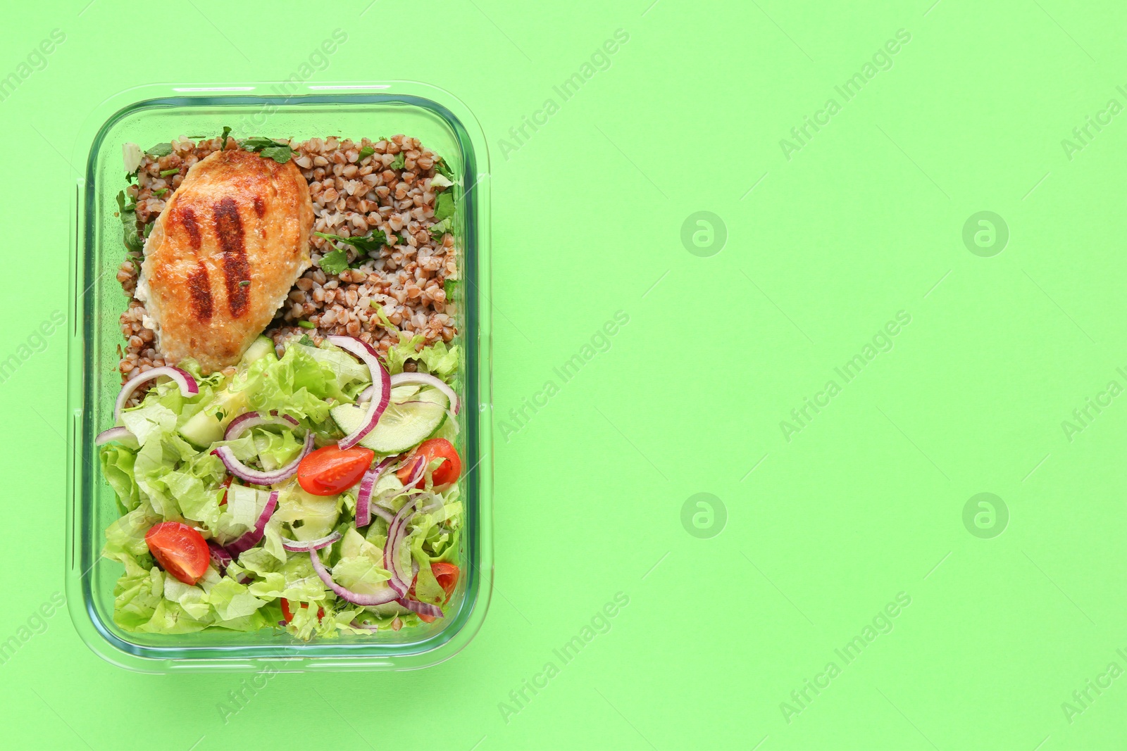 Photo of Healthy meal. Fresh salad, cutlet and buckwheat in glass container on green background, top view. Space for text