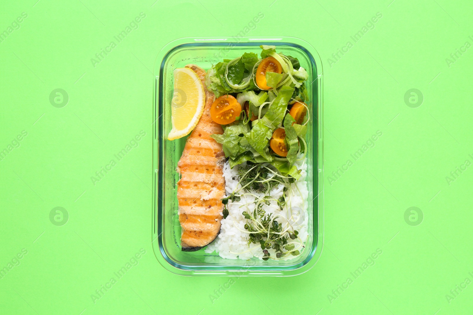 Photo of Healthy meal. Fresh salad, salmon and rice in glass container on green background, top view