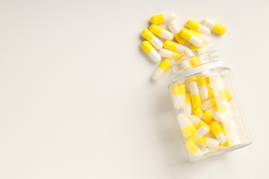 Photo of Antibiotic pills and bottle on white background, top view. Space for text