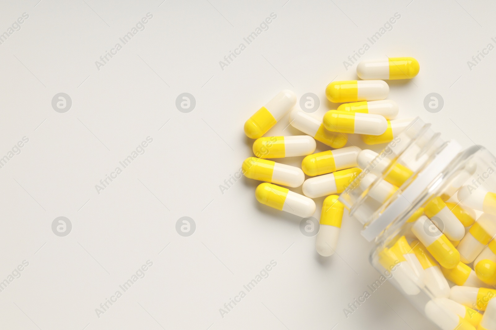 Photo of Antibiotic pills and bottle on white background, top view. Space for text