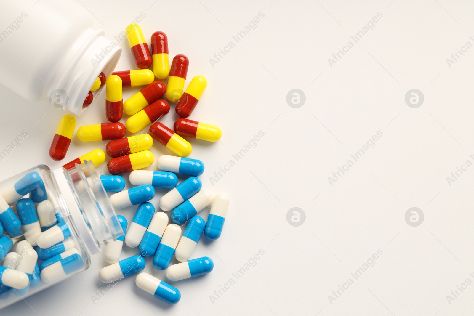 Photo of Antibiotic pills and bottles on white background, flat lay. Space for text