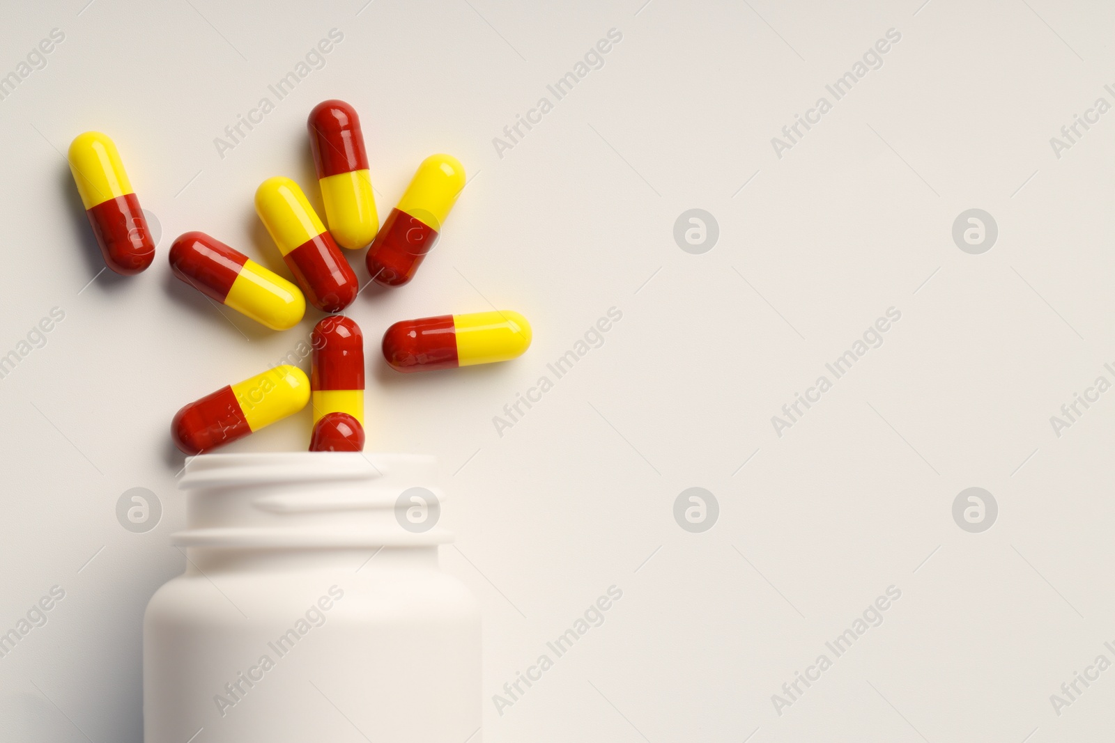 Photo of Antibiotic pills and bottle on white background, top view. Space for text