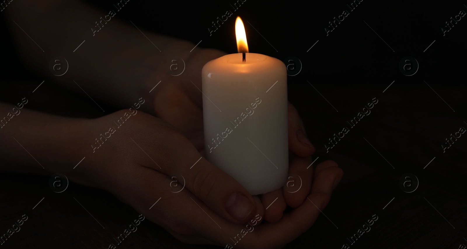 Photo of Woman holding burning candle on black background, closeup