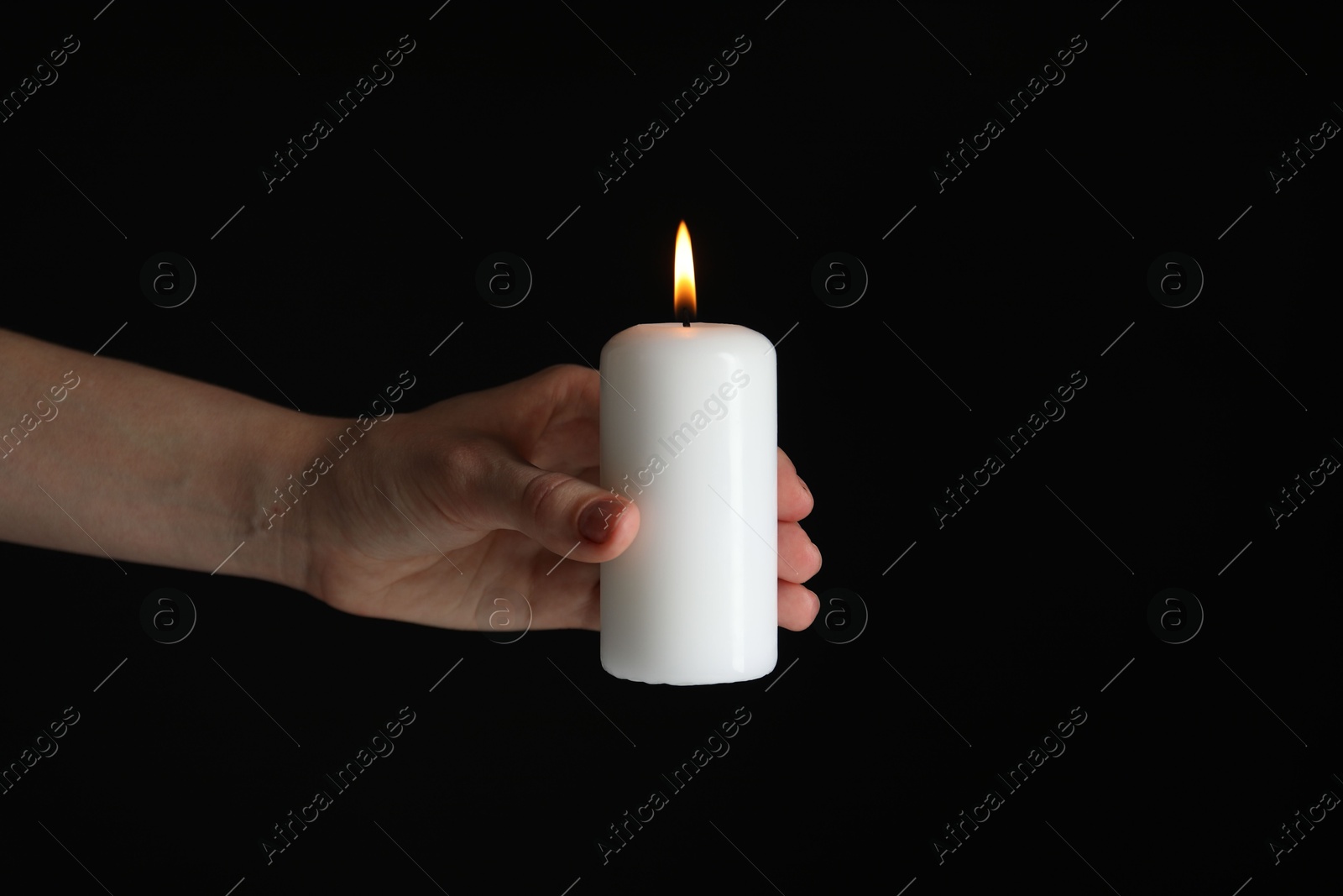 Photo of Woman holding burning candle on black background, closeup. Space for text