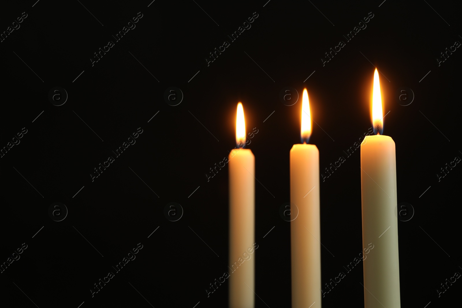 Photo of Burning candles on black background. Space for text