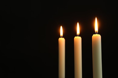 Photo of Burning candles on black background. Space for text