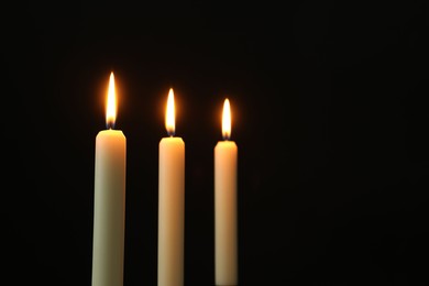 Photo of Burning candles on black background. Space for text