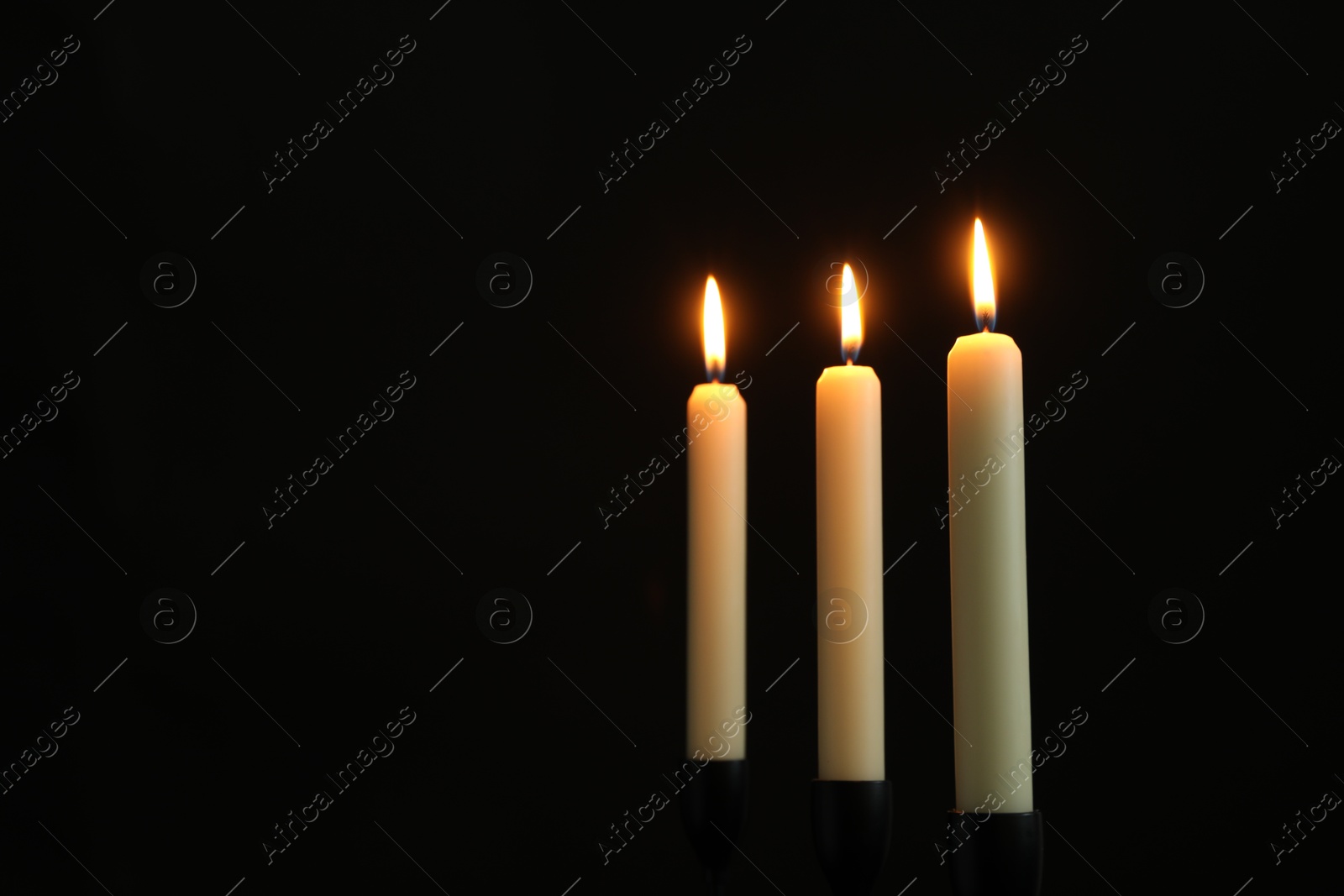 Photo of Burning candles on black background. Space for text