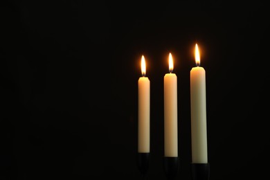 Photo of Burning candles on black background. Space for text