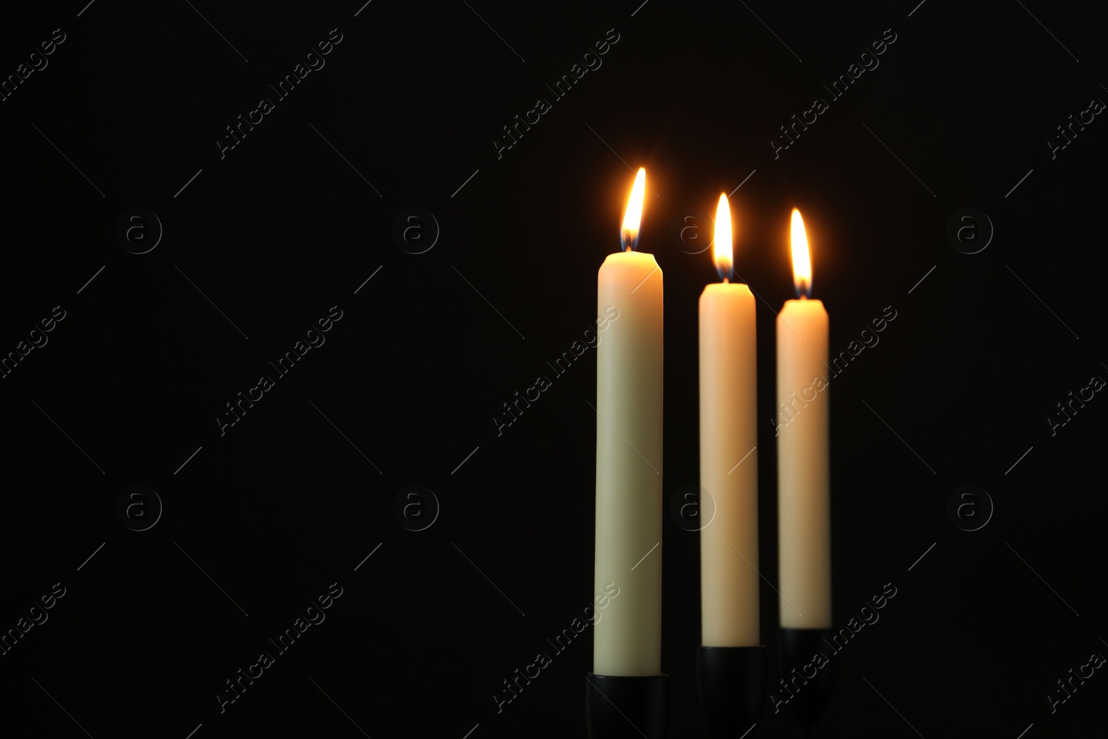 Photo of Burning candles on black background. Space for text