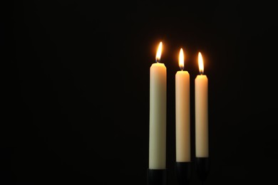 Photo of Burning candles on black background. Space for text