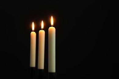 Photo of Burning candles on black background. Space for text