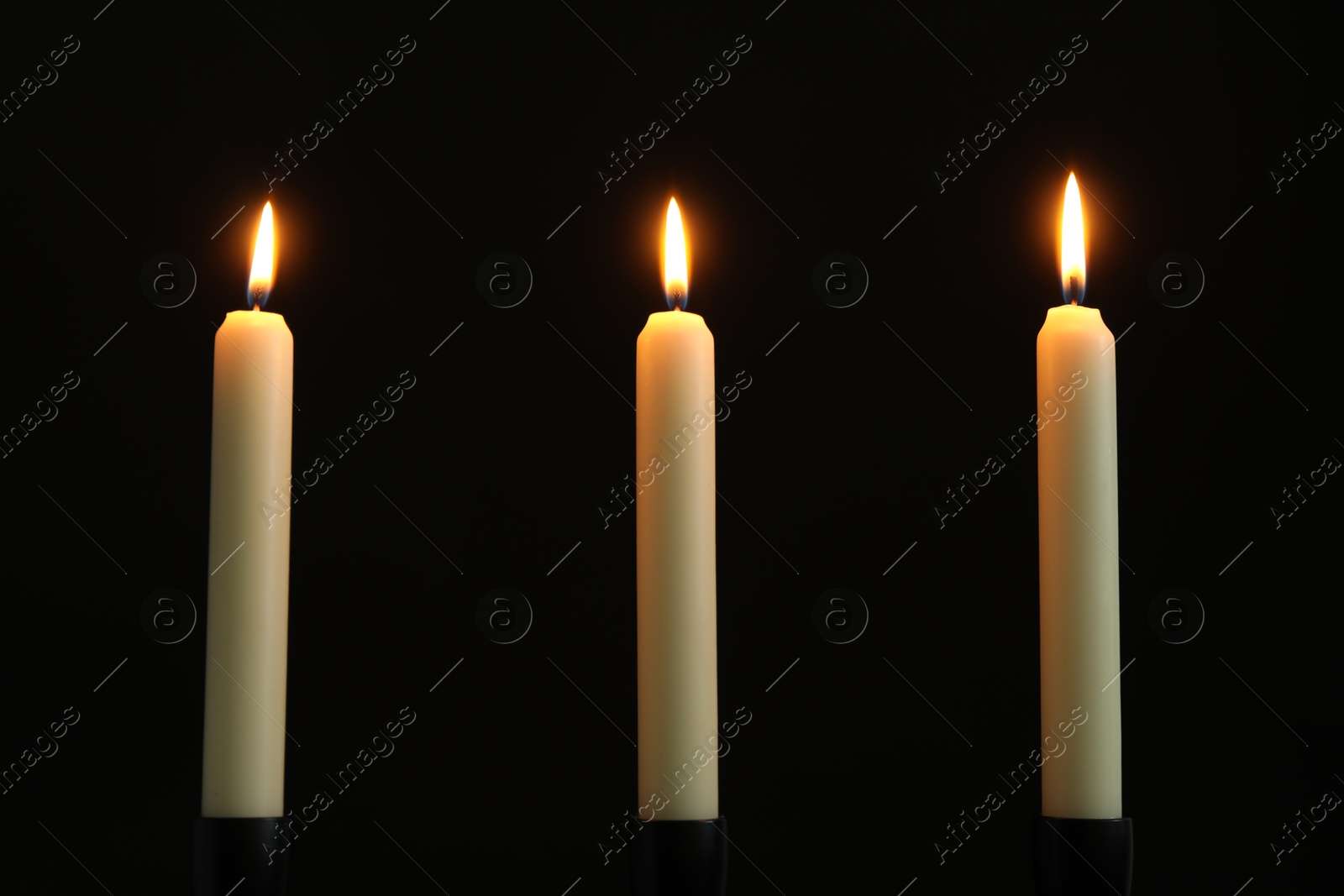 Photo of Many burning church candles on black background