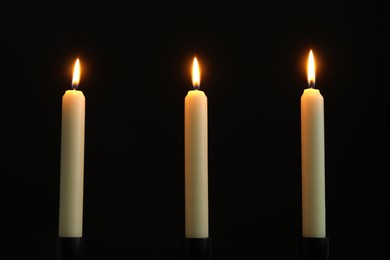 Photo of Many burning church candles on black background