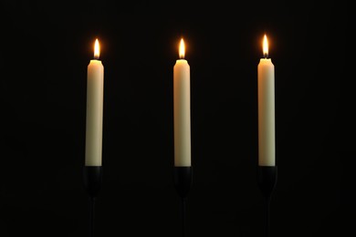 Photo of Many burning church candles on black background