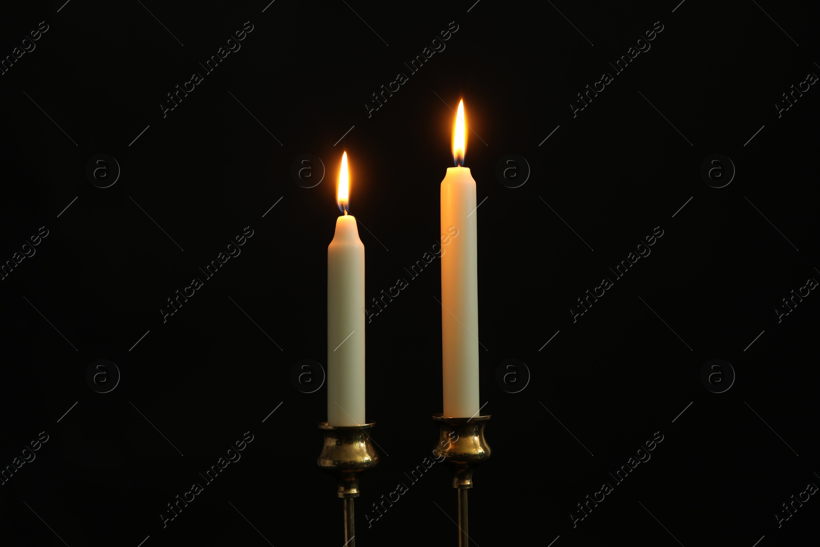 Photo of Two burning church candles on black background