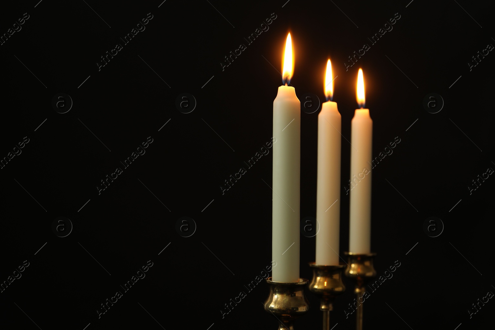 Photo of Burning candles on black background. Space for text